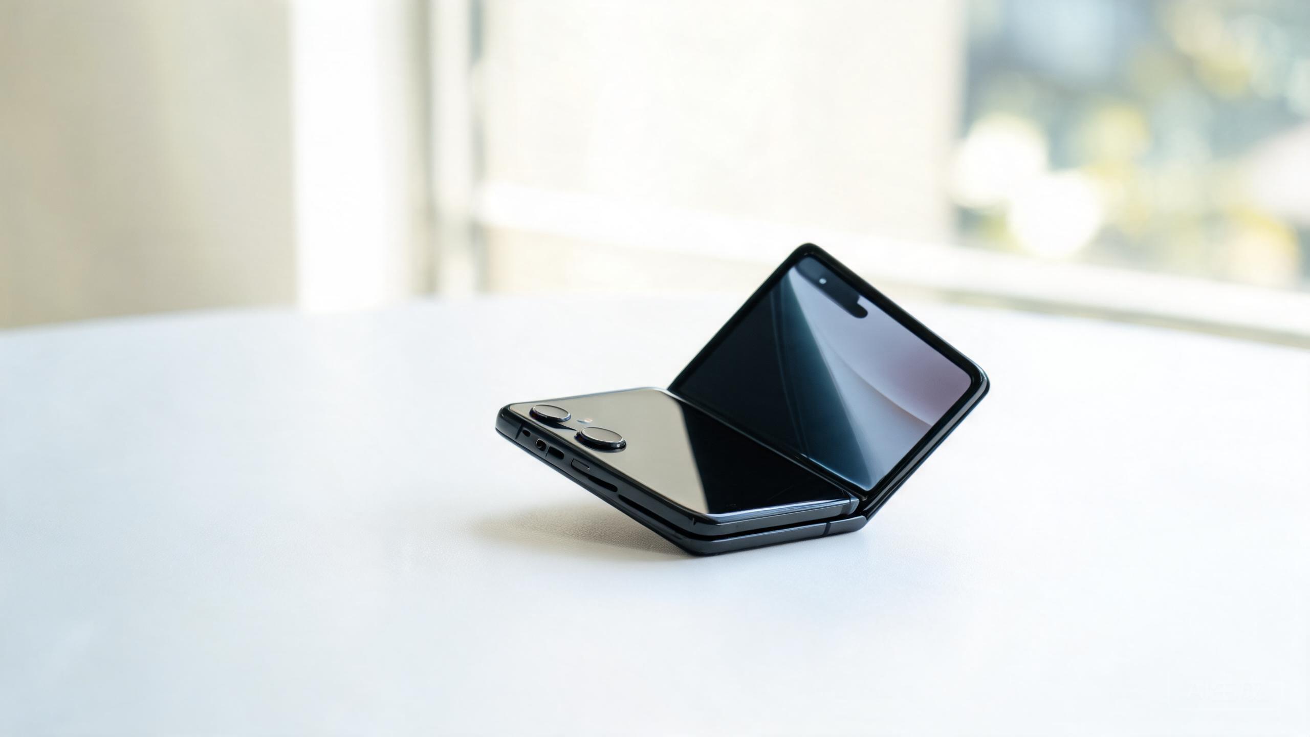 A folding phone half open sitting on a white desk